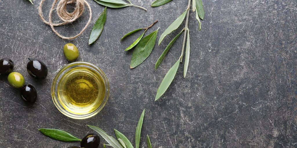 Glass bowl with olive oil and olive leafs