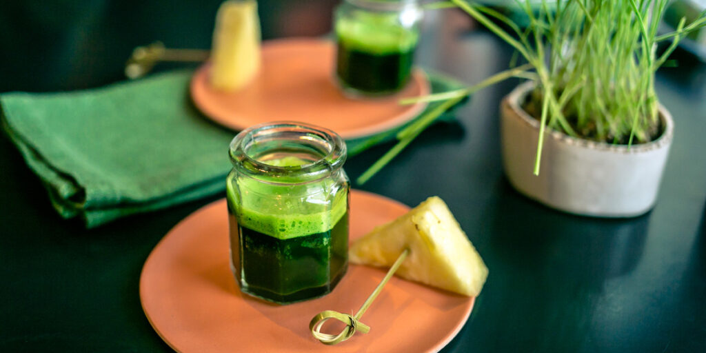 Wheatgrass juice with piece of pineapple on the plate